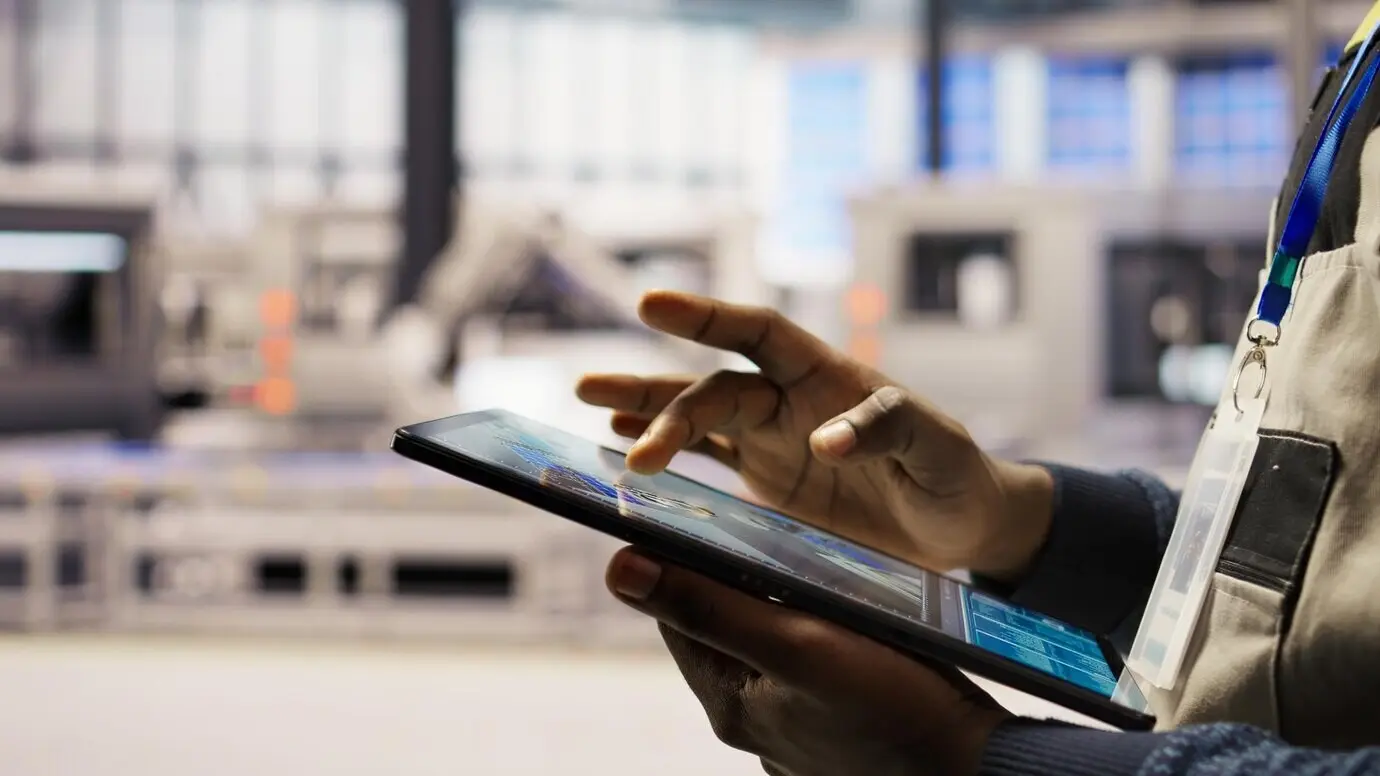 Крупный план инженера, использующего планшет для разработки планировок завода по производству солнечных панелей.